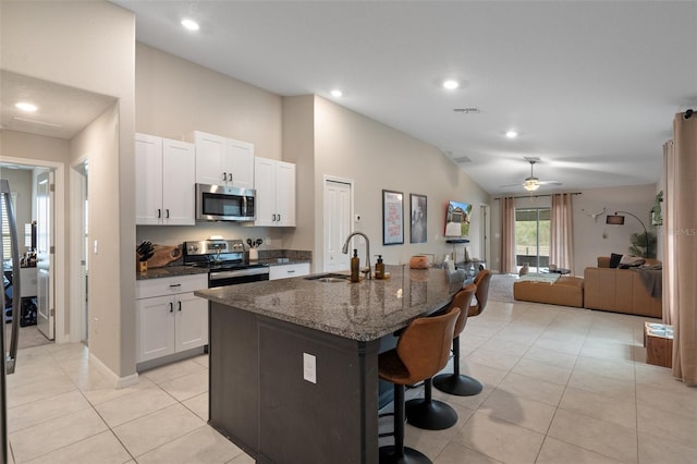 kitchen featuring sink, appliances with stainless steel finishes, a kitchen breakfast bar, an island with sink, and white cabinets