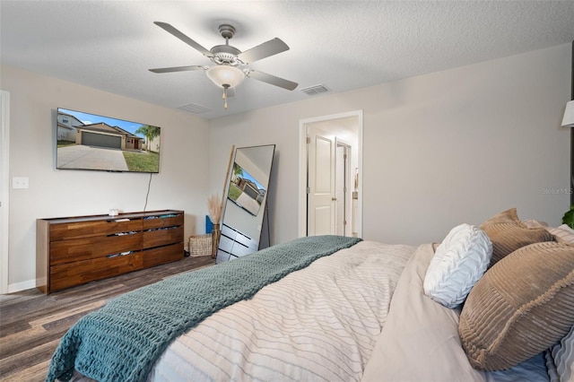 bedroom with ceiling fan, dark hardwood / wood-style floors, and a textured ceiling