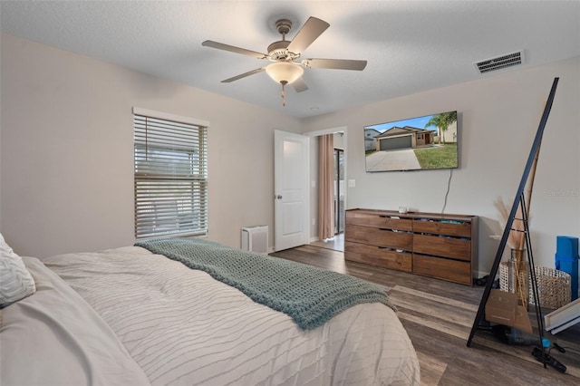 bedroom featuring ceiling fan, a textured ceiling, and dark hardwood / wood-style flooring