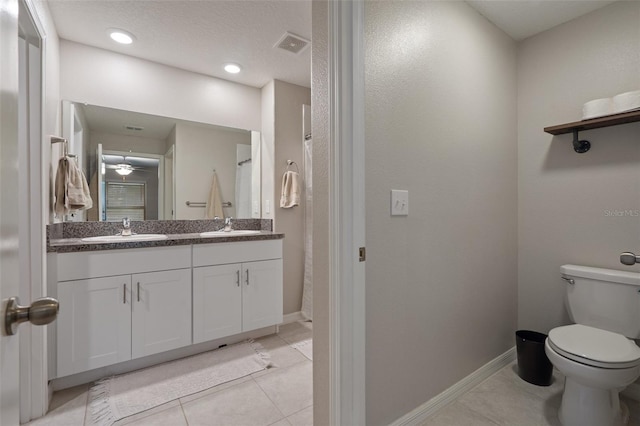 bathroom featuring vanity, toilet, tile patterned flooring, and a textured ceiling