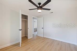 unfurnished bedroom with ceiling fan, light wood-type flooring, and a closet