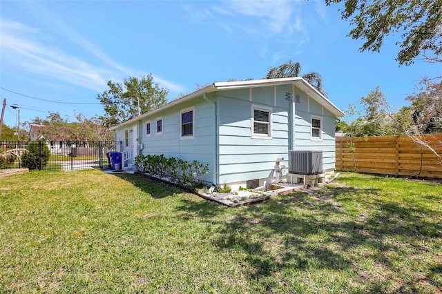 rear view of property with a lawn, a fenced backyard, and central AC