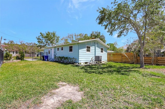 back of property with a lawn, a fenced backyard, and central air condition unit
