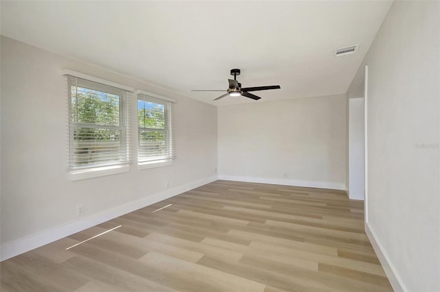 spare room with baseboards, light wood-style flooring, visible vents, and ceiling fan