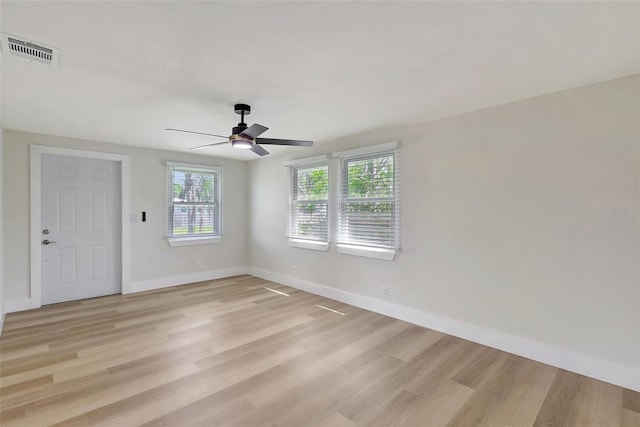 empty room featuring ceiling fan, a healthy amount of sunlight, light wood-style floors, and visible vents
