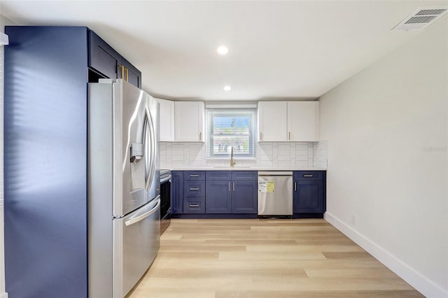 kitchen with white cabinets, stainless steel appliances, a sink, tasteful backsplash, and visible vents