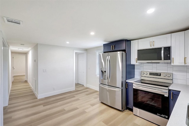 kitchen featuring light wood finished floors, stainless steel appliances, light countertops, visible vents, and blue cabinets