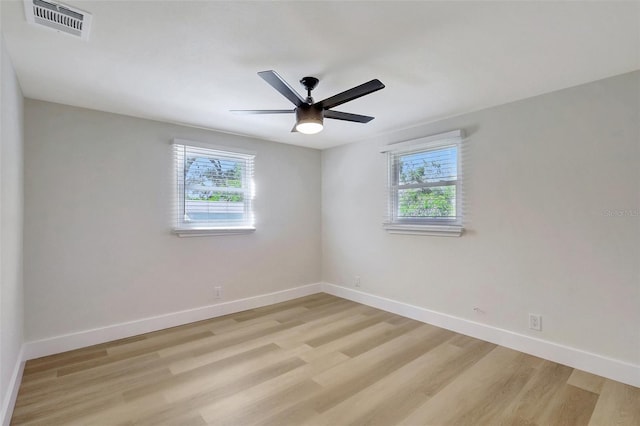 empty room featuring baseboards, light wood finished floors, visible vents, and plenty of natural light