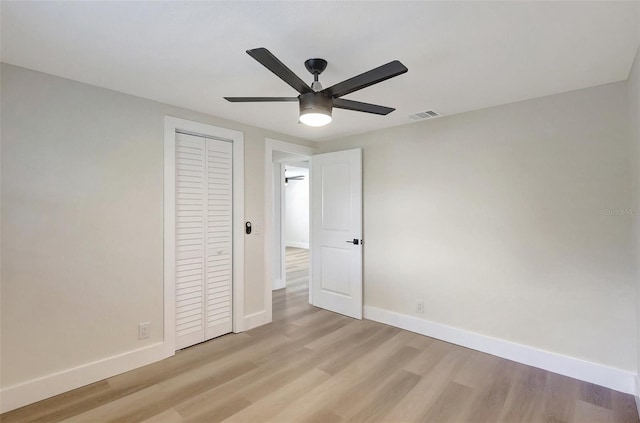 unfurnished bedroom featuring visible vents, light wood-type flooring, a closet, baseboards, and ceiling fan