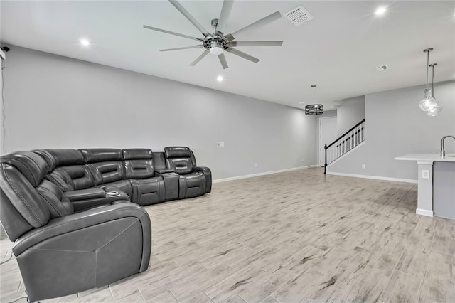 cinema room featuring ceiling fan and light wood-type flooring