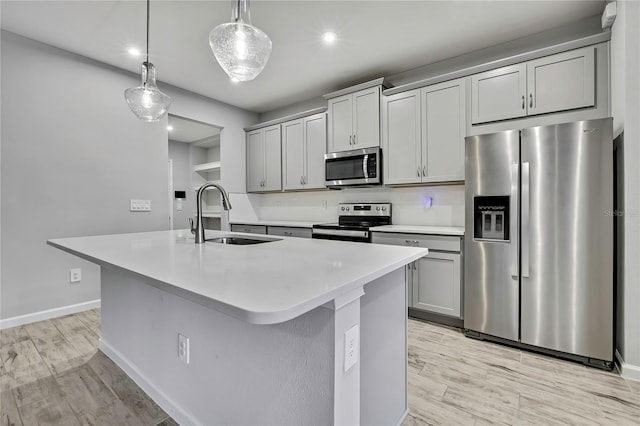 kitchen with sink, hanging light fixtures, a center island with sink, gray cabinets, and stainless steel appliances