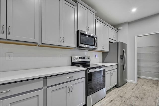 kitchen with appliances with stainless steel finishes, gray cabinetry, and backsplash