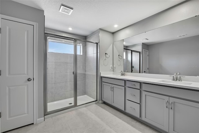 bathroom featuring vanity, tile patterned floors, an enclosed shower, and a textured ceiling