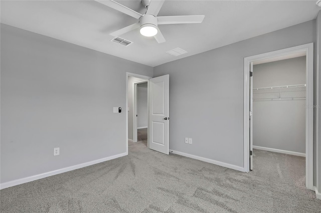 unfurnished bedroom featuring a spacious closet, light carpet, ceiling fan, and a closet