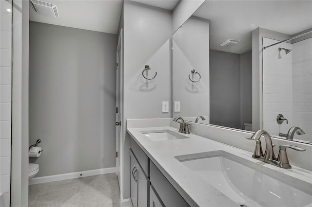 bathroom featuring vanity, tile patterned floors, toilet, and tiled shower