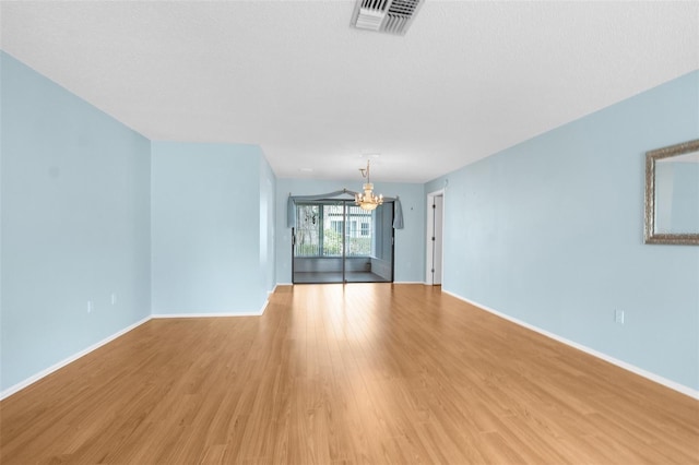 unfurnished living room featuring light wood-type flooring and an inviting chandelier