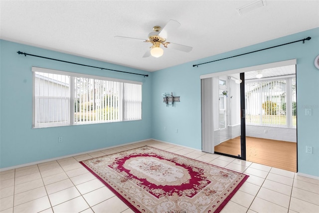 tiled empty room featuring ceiling fan, plenty of natural light, and a textured ceiling