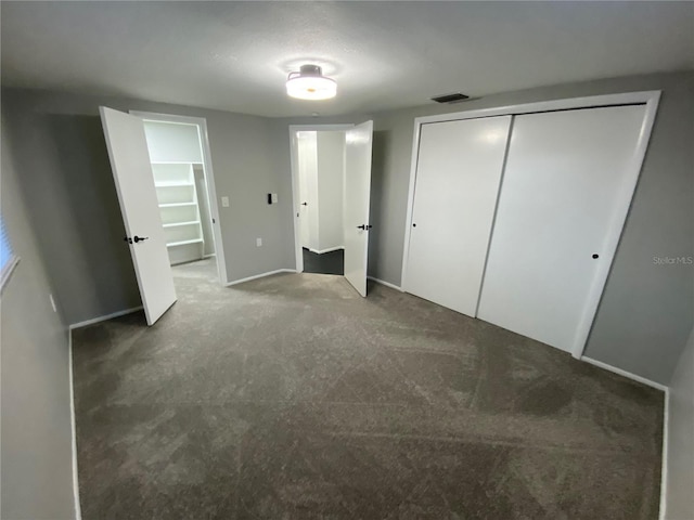 unfurnished bedroom with dark carpet and a closet