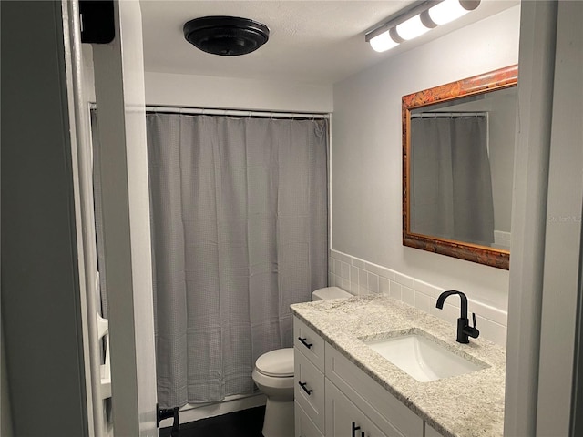 bathroom featuring vanity, tile walls, and toilet