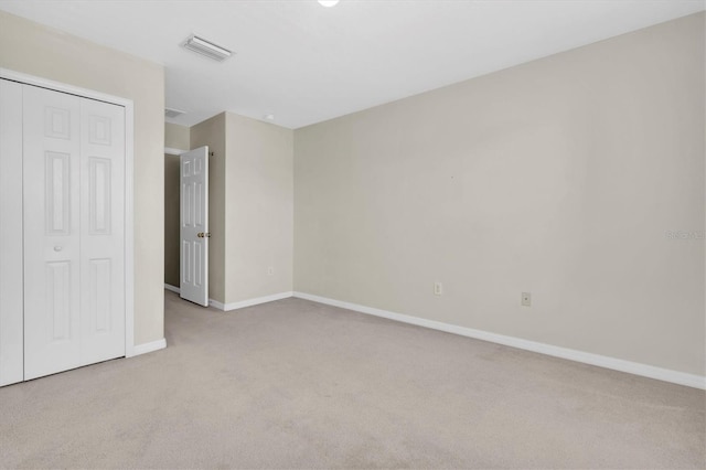 unfurnished bedroom with light colored carpet and a closet