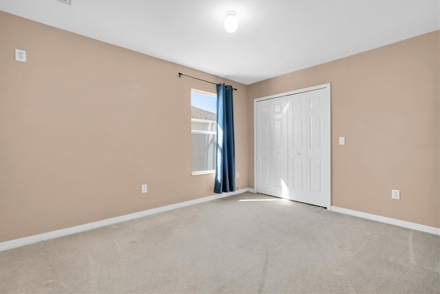 unfurnished bedroom with light colored carpet and a closet