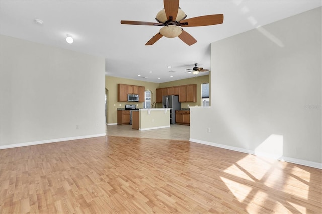 unfurnished living room featuring ceiling fan, sink, and light hardwood / wood-style floors