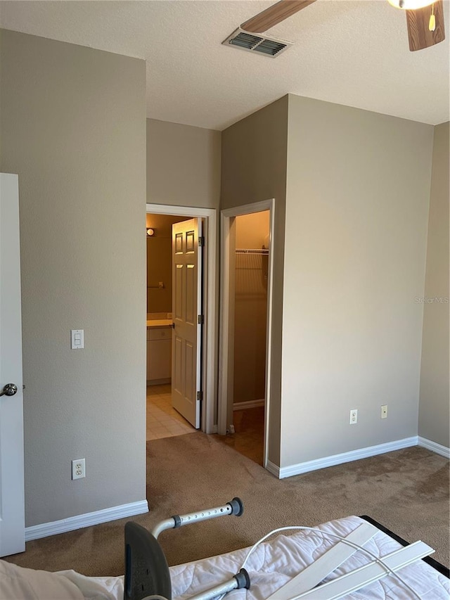 carpeted bedroom featuring a spacious closet, ensuite bath, a closet, and a textured ceiling