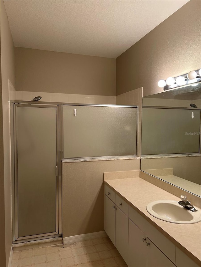 bathroom featuring vanity, a shower with shower door, and a textured ceiling