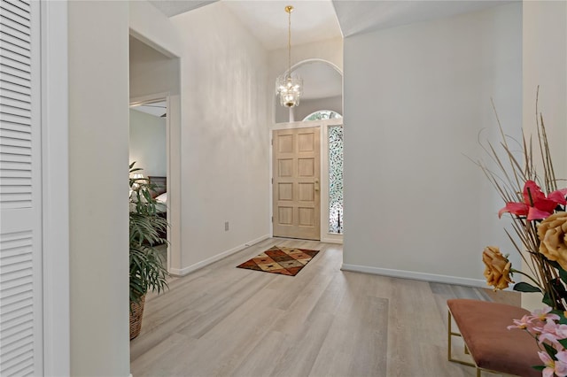 foyer entrance with light hardwood / wood-style flooring and a chandelier