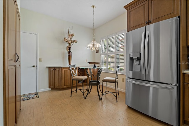 kitchen featuring decorative light fixtures, a chandelier, light wood-type flooring, and stainless steel fridge with ice dispenser