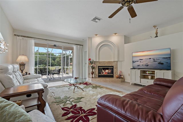 living room with ceiling fan, a high end fireplace, and light hardwood / wood-style floors