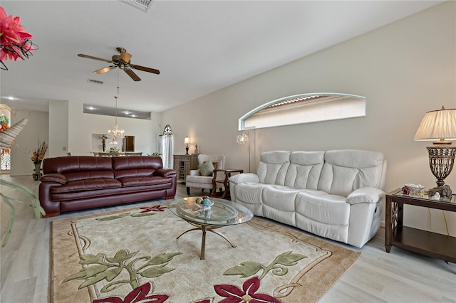 living room with ceiling fan with notable chandelier and light hardwood / wood-style flooring