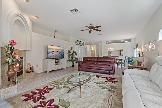 living room with ceiling fan, a fireplace, and light hardwood / wood-style floors