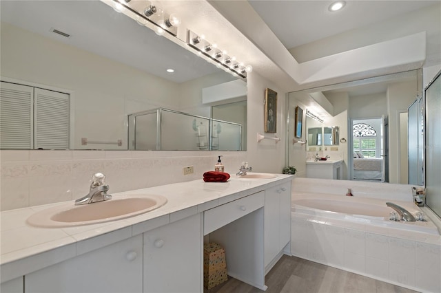 bathroom with hardwood / wood-style flooring, vanity, separate shower and tub, and tasteful backsplash