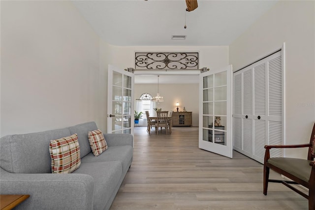 living room featuring ceiling fan with notable chandelier, wood-type flooring, and french doors