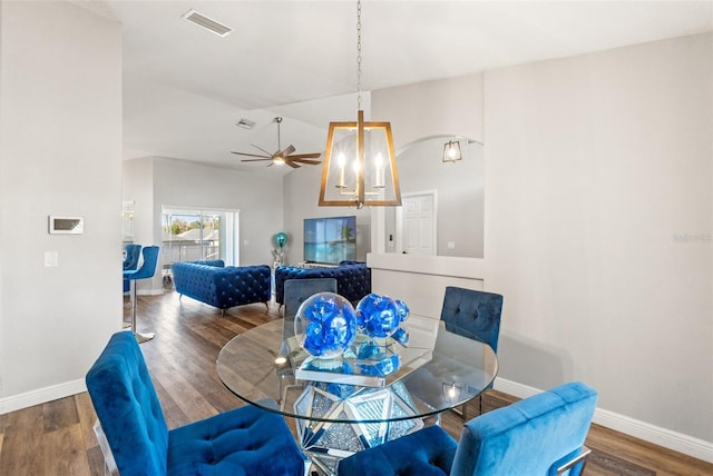 dining area with lofted ceiling, dark wood-type flooring, and an inviting chandelier