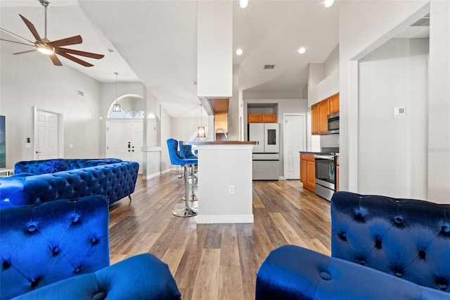 living room featuring vaulted ceiling, ceiling fan, and light hardwood / wood-style flooring