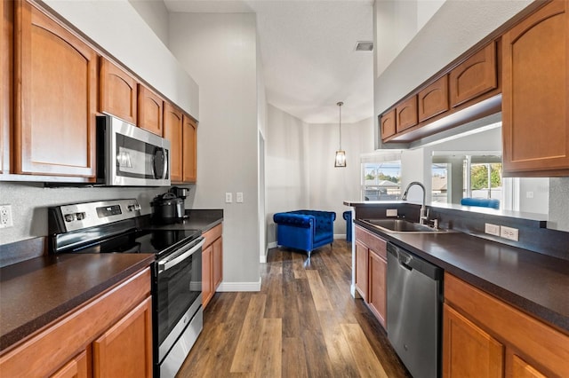 kitchen with sink, dark wood-type flooring, stainless steel appliances, and hanging light fixtures