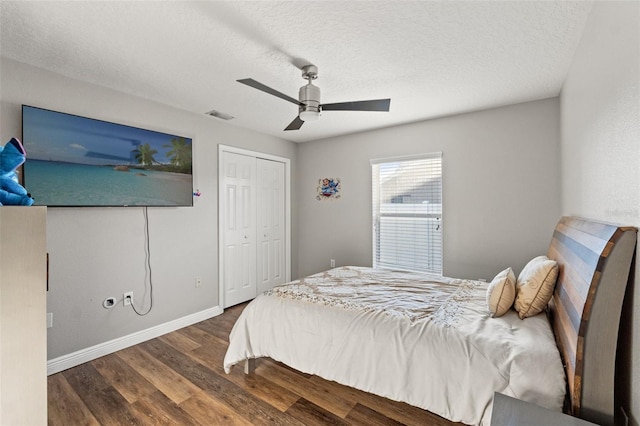 bedroom with dark wood-type flooring, ceiling fan, a closet, and a textured ceiling