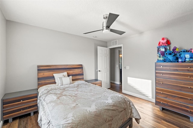 bedroom with hardwood / wood-style floors, a textured ceiling, and ceiling fan