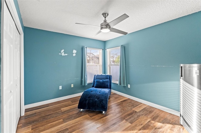 sitting room with hardwood / wood-style flooring, ceiling fan, and a textured ceiling