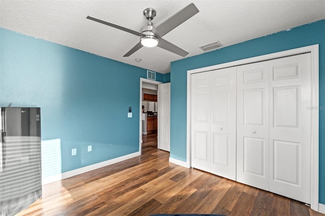 unfurnished bedroom featuring ceiling fan, dark hardwood / wood-style floors, a closet, and a textured ceiling