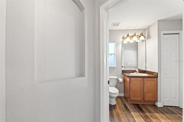 bathroom featuring hardwood / wood-style flooring, vanity, toilet, and a textured ceiling