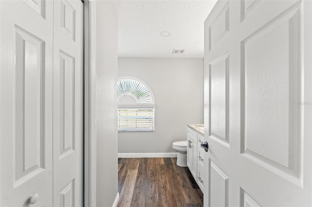 bathroom with vanity, a textured ceiling, wood-type flooring, and toilet