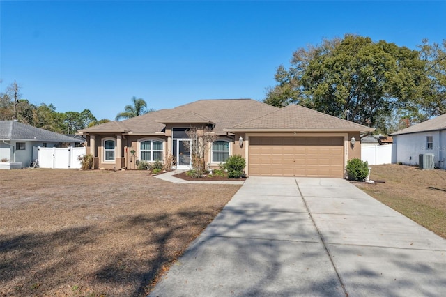 ranch-style house featuring a garage, a front yard, and central air condition unit