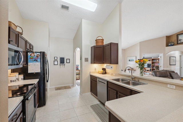 kitchen featuring dark brown cabinetry, sink, light tile patterned floors, and stainless steel appliances