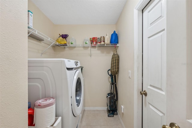 laundry room with a textured ceiling, washing machine and clothes dryer, and light tile patterned flooring