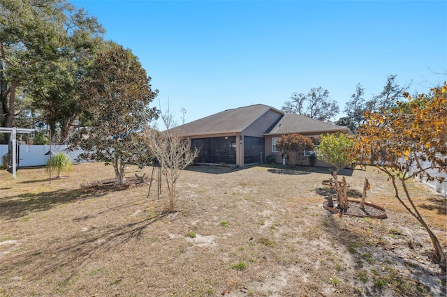 back of house featuring a lawn and a sunroom