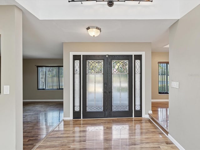 foyer entrance with light wood finished floors, french doors, and baseboards