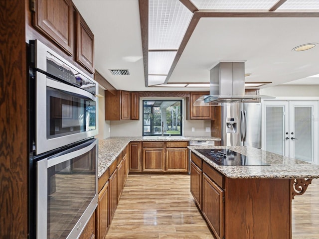 kitchen with visible vents, a breakfast bar, stainless steel appliances, light wood-style floors, and a sink